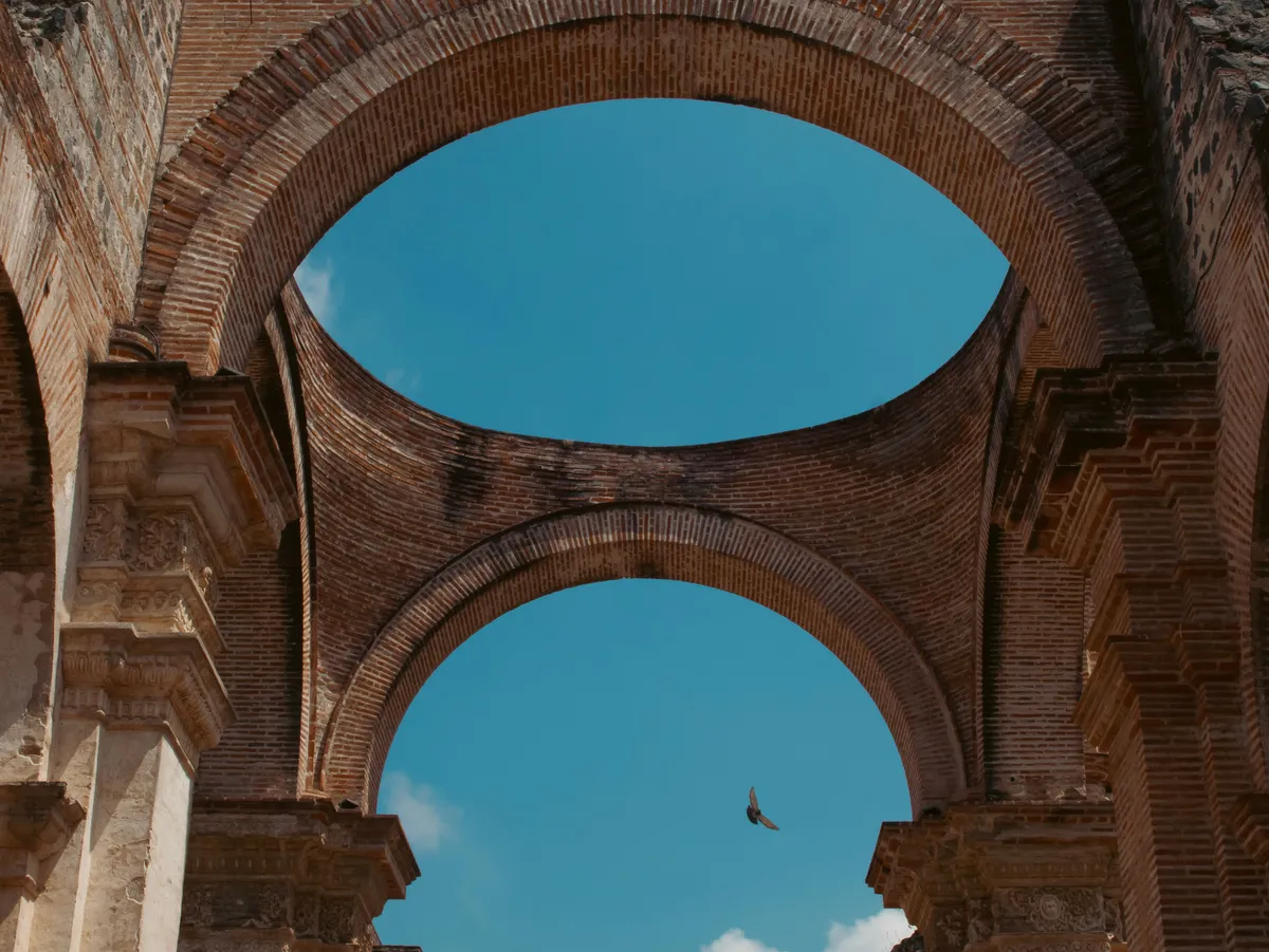 Historic brick arches in Antigua Guatemala with a bird flying through
