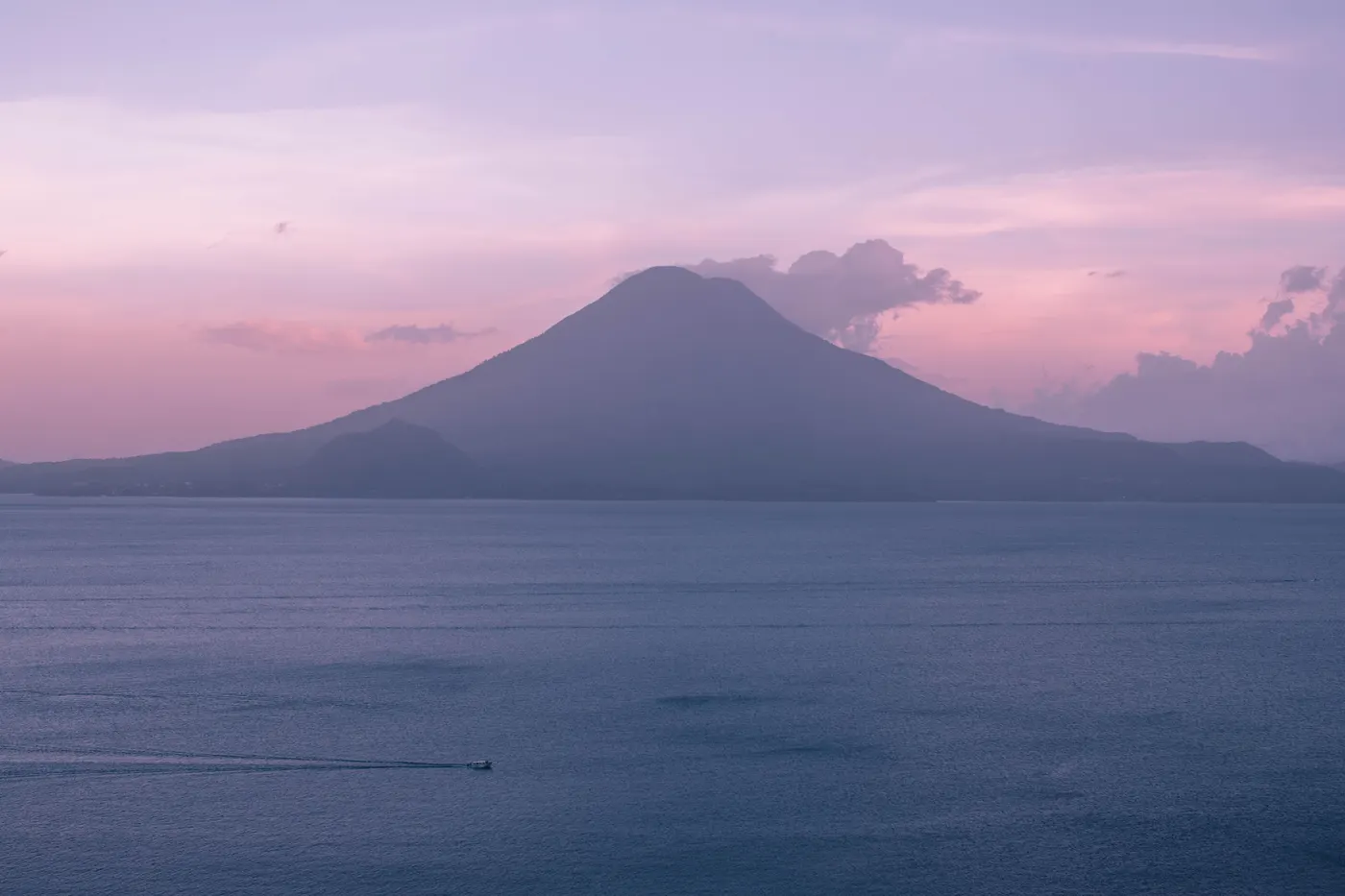 Volcano silhouetted against a dusky pink sky over Lake Atitlán