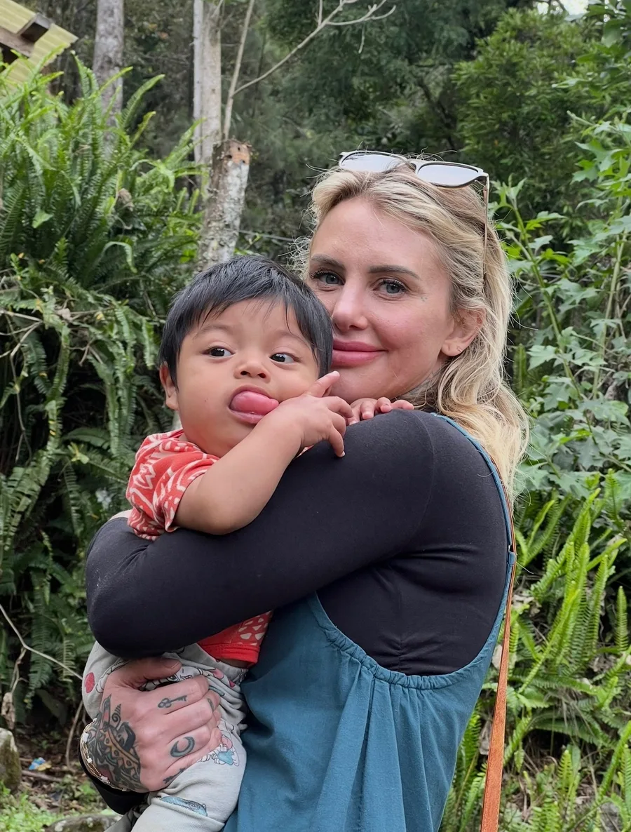 A team member holding a laughing Guatemalan toddler in a lush garden