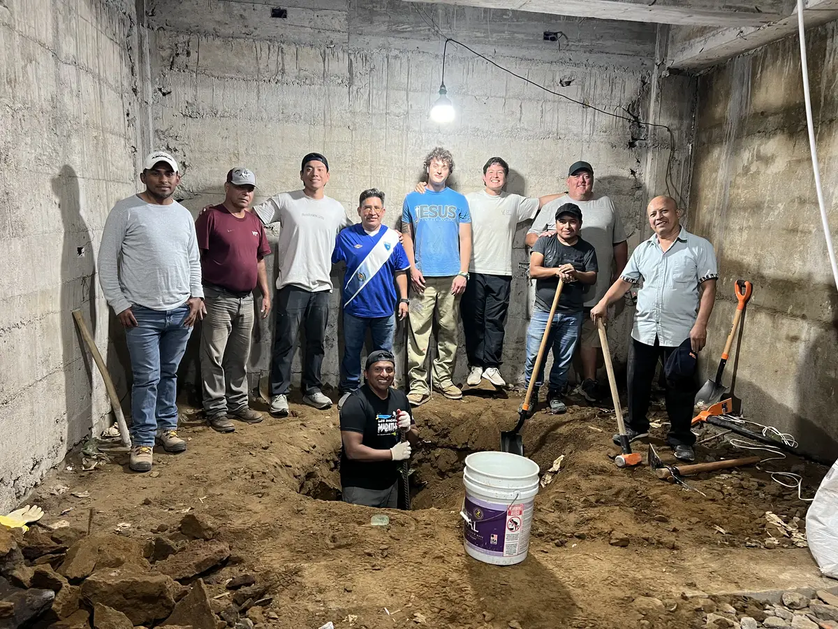 A work team of local believers and visitors pausing mid-project inside a concrete building